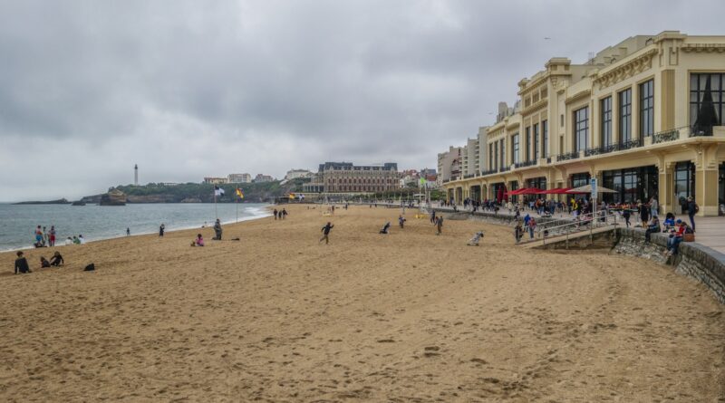 a sandy beach with people sitting and walking on it