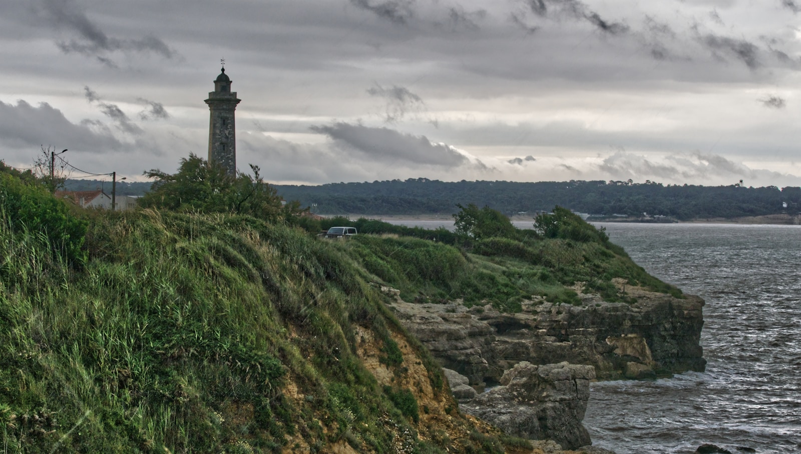 white and black lighthouse on green grass field near body of water during daytime